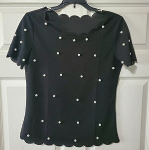 Black blouse with white pearls on it.